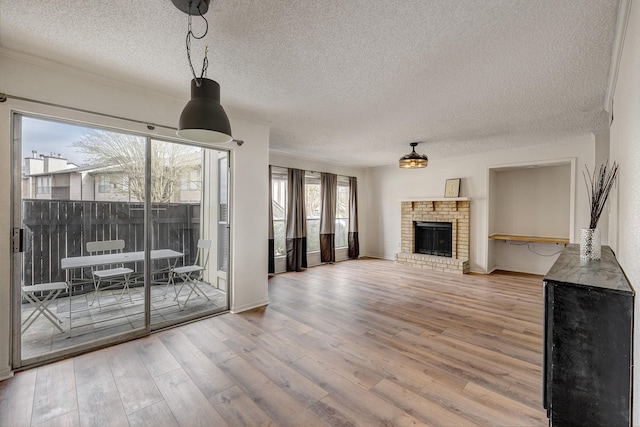 unfurnished living room with a brick fireplace, crown molding, a textured ceiling, and wood finished floors