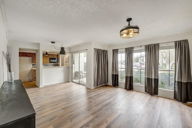 unfurnished living room featuring light wood-style flooring, crown molding, and a textured ceiling