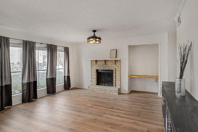 unfurnished living room with visible vents, a textured ceiling, a brick fireplace, and light wood-style flooring