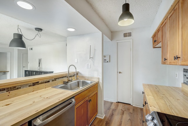 kitchen with a sink, wooden counters, visible vents, and stainless steel dishwasher