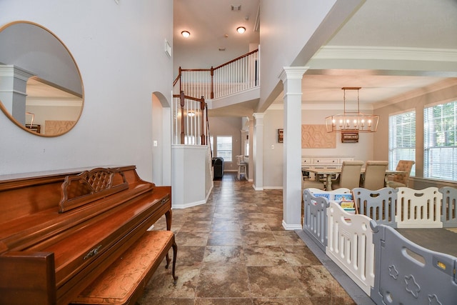 foyer entrance with arched walkways, crown molding, ornate columns, a chandelier, and baseboards