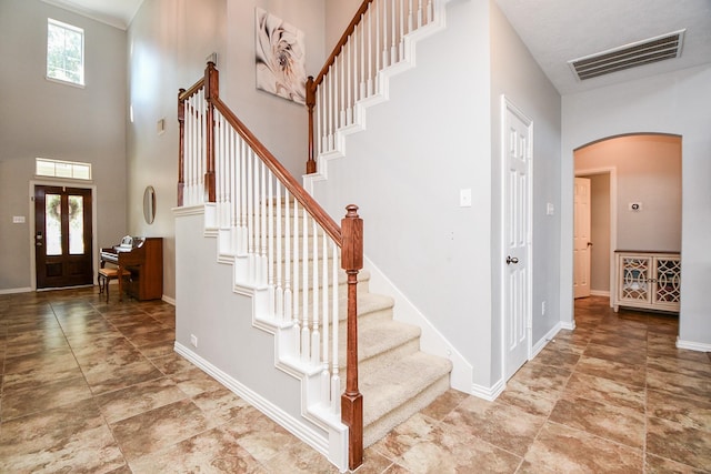 foyer featuring arched walkways, baseboards, visible vents, and a healthy amount of sunlight