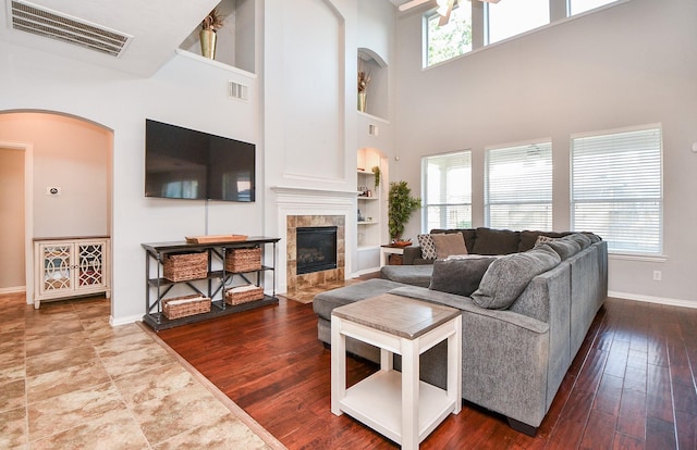 living room featuring a tile fireplace, visible vents, and a healthy amount of sunlight