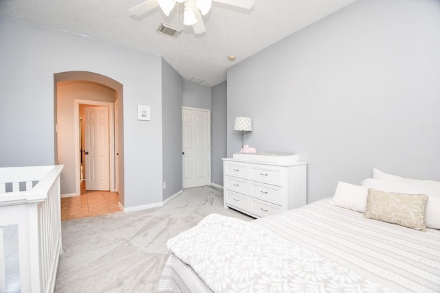 bedroom featuring arched walkways, light colored carpet, visible vents, vaulted ceiling, and baseboards