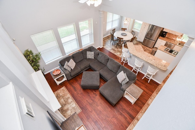 living area featuring a high ceiling, baseboards, and wood finished floors