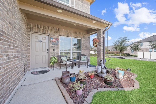 property entrance with a yard, brick siding, and a porch