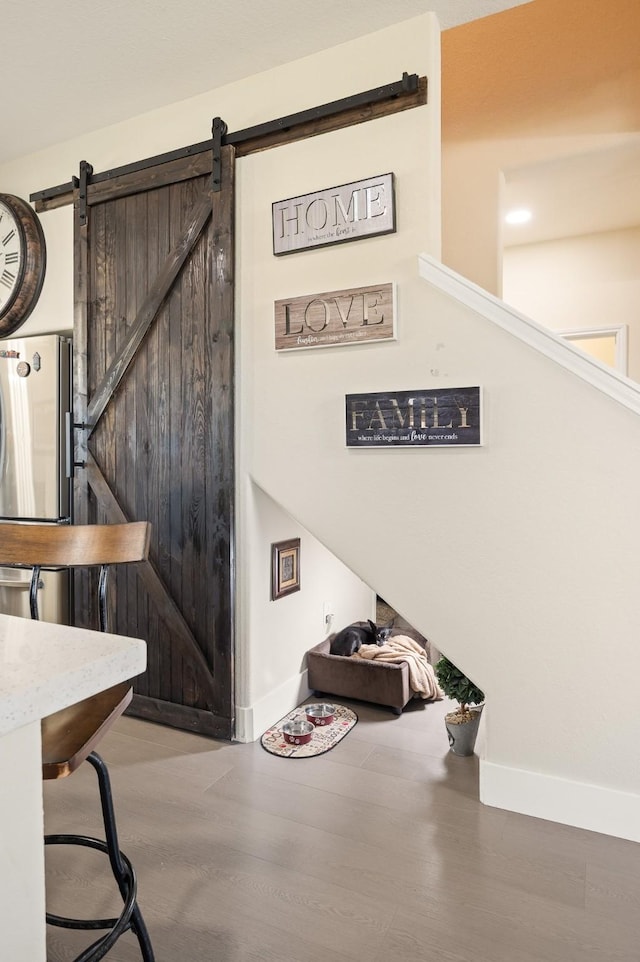 interior space featuring a barn door, baseboards, and wood finished floors