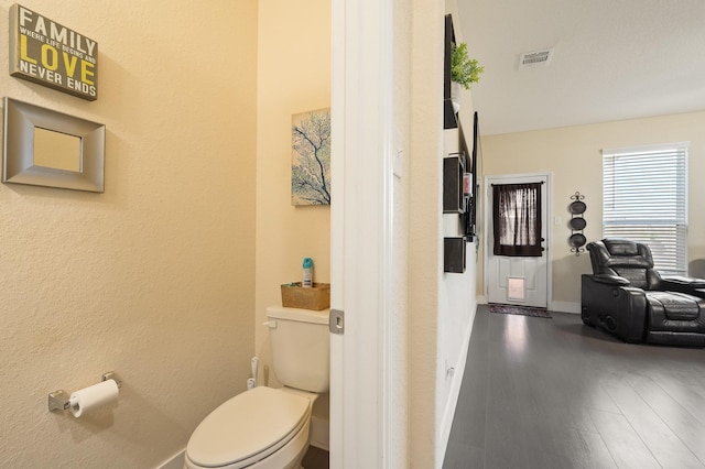 bathroom with toilet, baseboards, visible vents, and wood finished floors