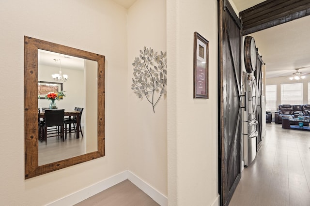 hallway featuring a chandelier, light wood-type flooring, and baseboards