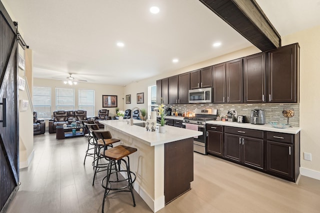 kitchen with stainless steel appliances, a sink, a kitchen bar, and dark brown cabinets