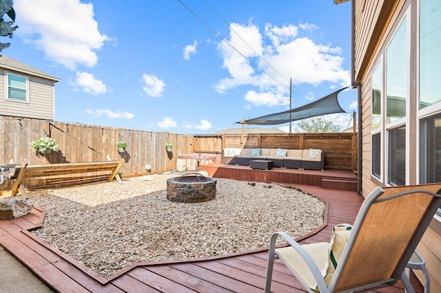 deck featuring a fenced backyard and an outdoor living space with a fire pit