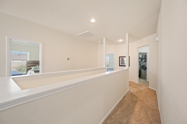 corridor featuring recessed lighting, light colored carpet, visible vents, baseboards, and washer / clothes dryer