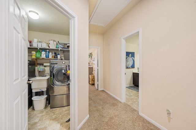 laundry area featuring laundry area, attic access, washer / dryer, carpet floors, and a sink