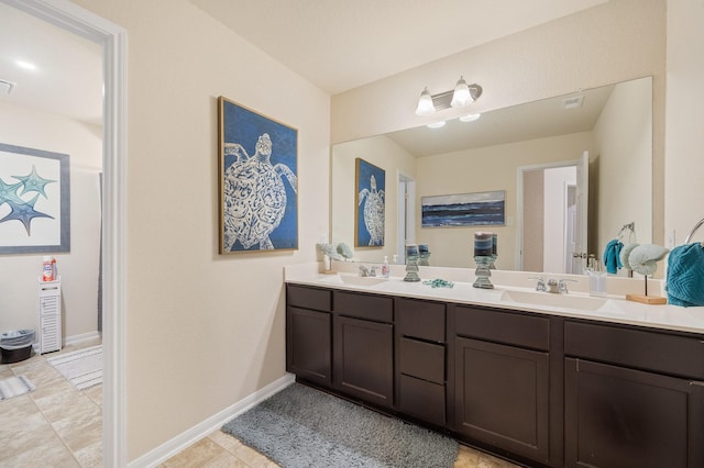 bathroom with double vanity, a sink, visible vents, and baseboards