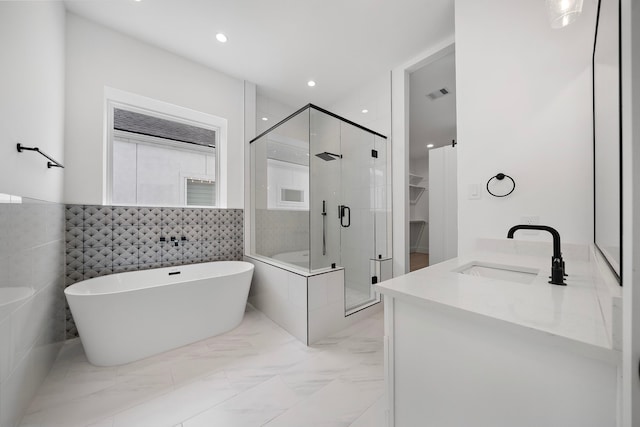 bathroom with marble finish floor, recessed lighting, a freestanding bath, a shower stall, and vanity