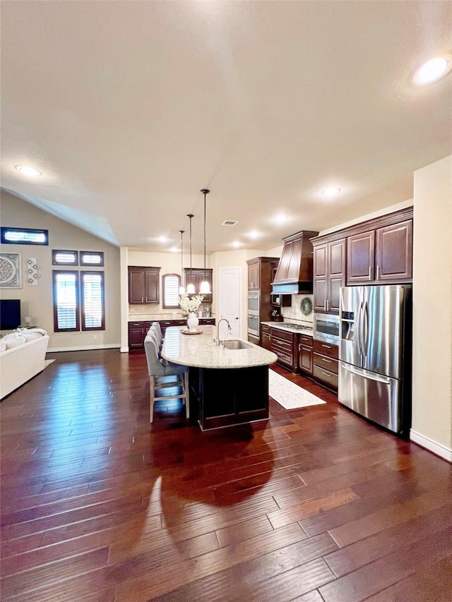 kitchen featuring appliances with stainless steel finishes, a breakfast bar, premium range hood, and dark wood-style floors