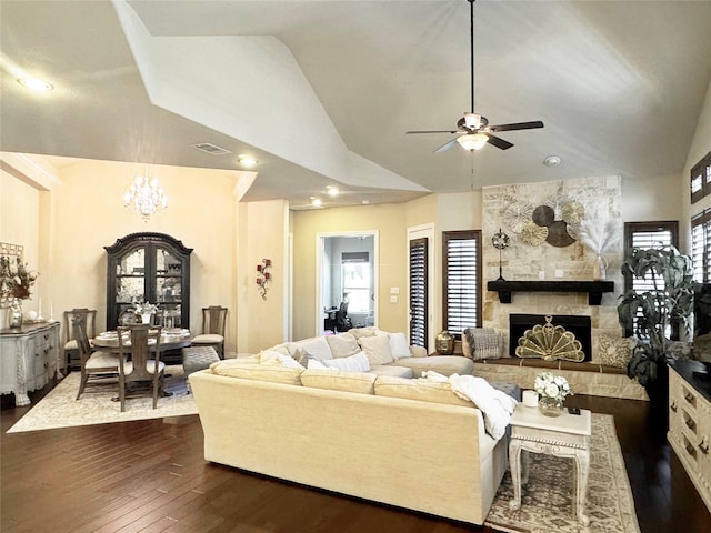 living room with visible vents, lofted ceiling, dark wood-type flooring, a fireplace, and ceiling fan with notable chandelier