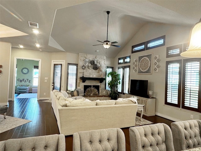 living area with baseboards, visible vents, dark wood-type flooring, a fireplace, and high vaulted ceiling