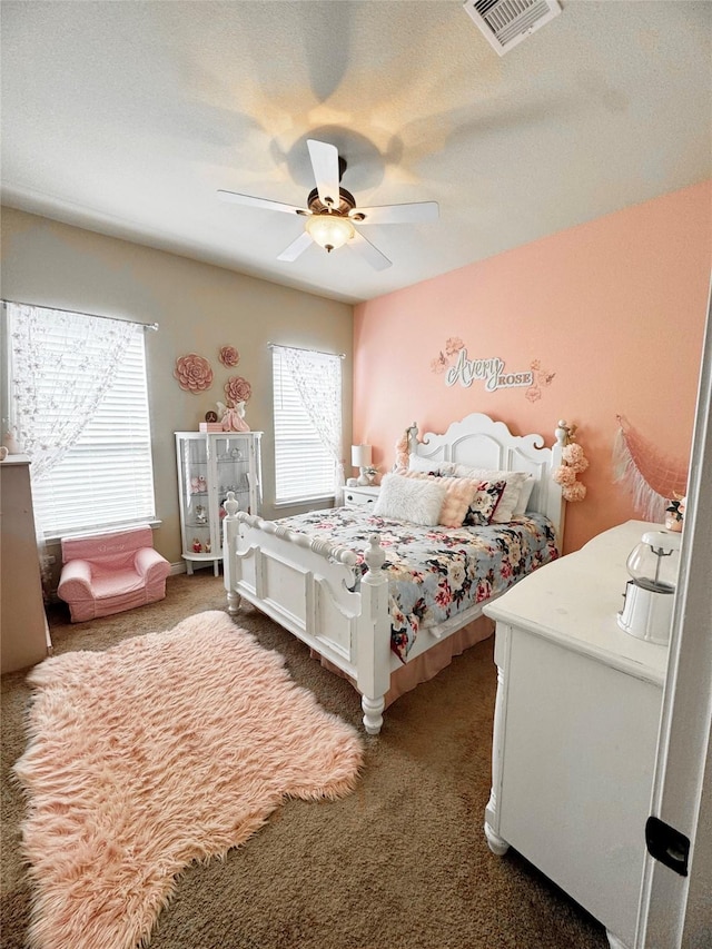 carpeted bedroom with a ceiling fan and visible vents