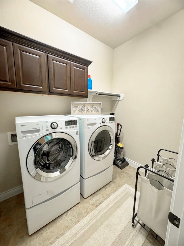 washroom with washing machine and dryer, cabinet space, and baseboards