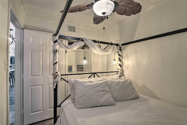 bedroom with ceiling fan, a textured wall, ornamental molding, and visible vents