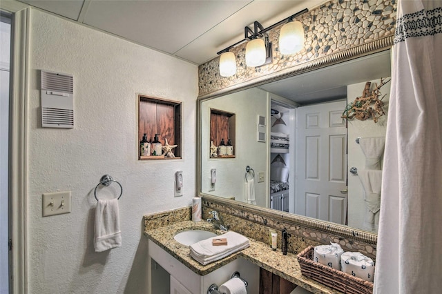 bathroom with a textured wall and vanity