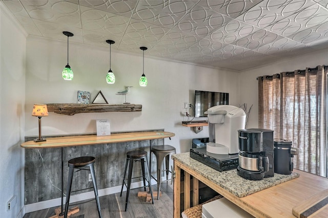 kitchen featuring butcher block countertops, wood finished floors, baseboards, an ornate ceiling, and crown molding