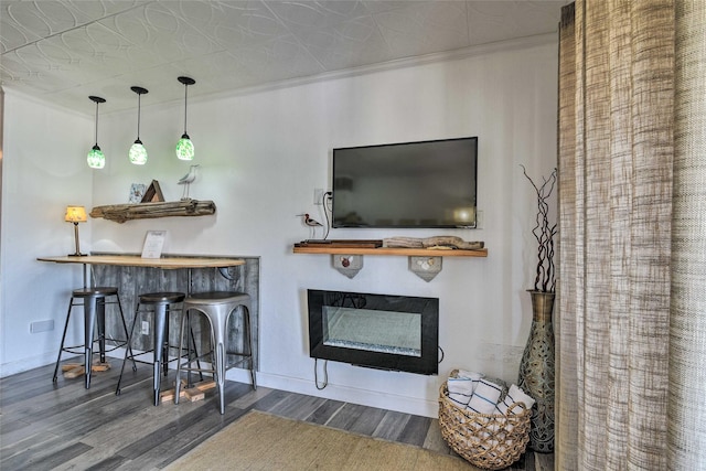 living room with ornamental molding, a fireplace, baseboards, and wood finished floors