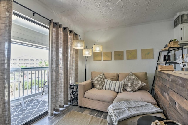 living area with wood finished floors, an ornate ceiling, and crown molding