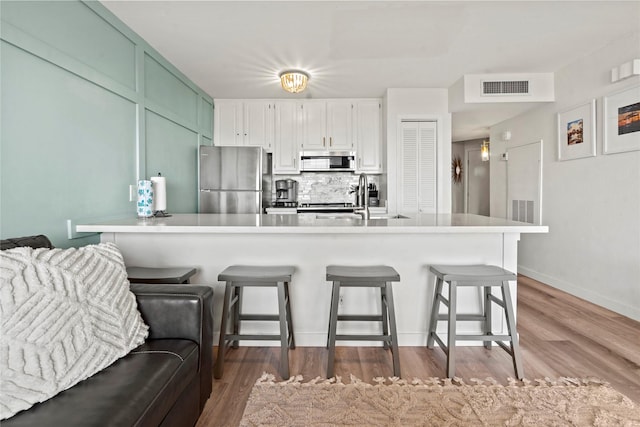 kitchen with stainless steel appliances, a sink, visible vents, tasteful backsplash, and a kitchen bar