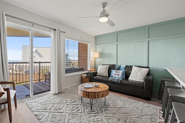 living area with ceiling fan and a decorative wall