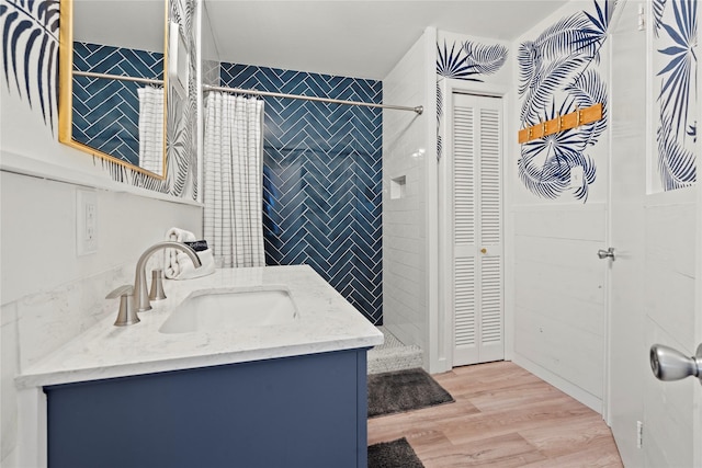 full bathroom with a closet, vanity, tile walls, and wood finished floors