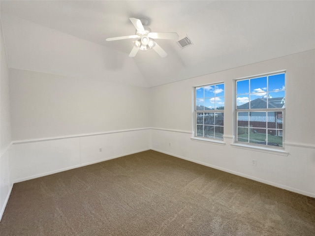 unfurnished room featuring lofted ceiling, dark colored carpet, ceiling fan, and visible vents