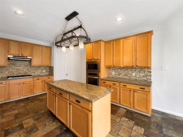 kitchen with stone tile floors, tasteful backsplash, appliances with stainless steel finishes, a kitchen island, and baseboards