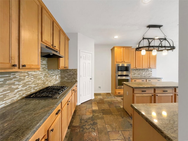 kitchen with under cabinet range hood, baseboards, appliances with stainless steel finishes, tasteful backsplash, and stone tile flooring