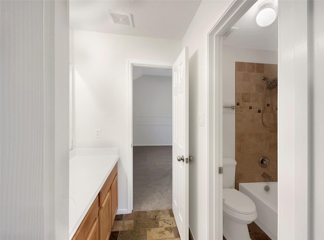 bathroom with visible vents, toilet, stone finish floor, tub / shower combination, and vanity