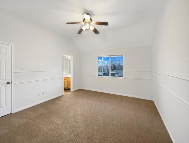 spare room featuring carpet floors, baseboards, vaulted ceiling, and a ceiling fan