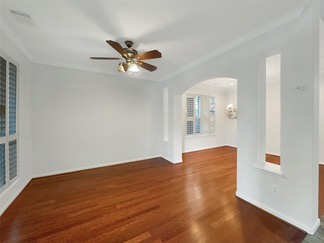 unfurnished room featuring arched walkways, visible vents, baseboards, and wood finished floors