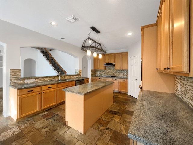 kitchen with stone tile floors, visible vents, a kitchen island, stovetop, and stainless steel dishwasher