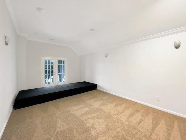 carpeted spare room featuring vaulted ceiling, crown molding, baseboards, and french doors