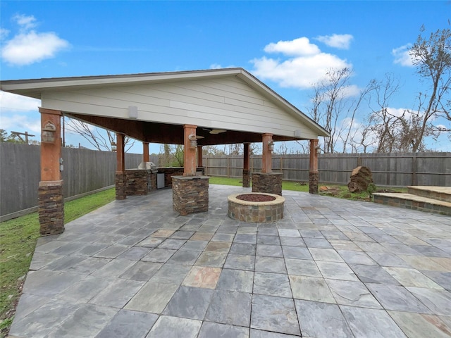 view of patio with an outdoor fire pit, a fenced backyard, an outdoor kitchen, and a gazebo