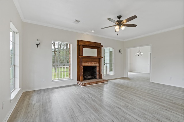 unfurnished living room with ornamental molding, ceiling fan with notable chandelier, visible vents, and light wood-type flooring