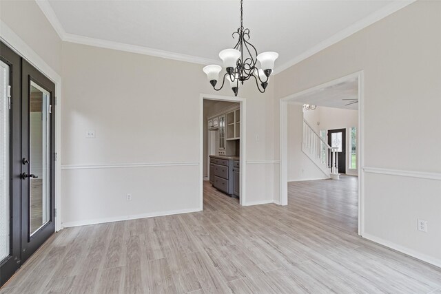 spare room featuring stairway, baseboards, ornamental molding, a notable chandelier, and light wood-type flooring