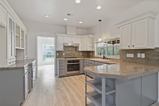 kitchen featuring oven, visible vents, open shelves, a sink, and a peninsula