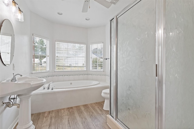 bathroom with toilet, a stall shower, wood finished floors, a bath, and ceiling fan