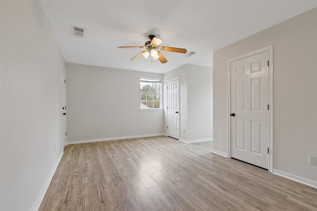 empty room featuring visible vents, baseboards, light wood-type flooring, and a ceiling fan