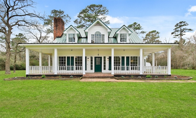 farmhouse with covered porch, a chimney, a front yard, and metal roof