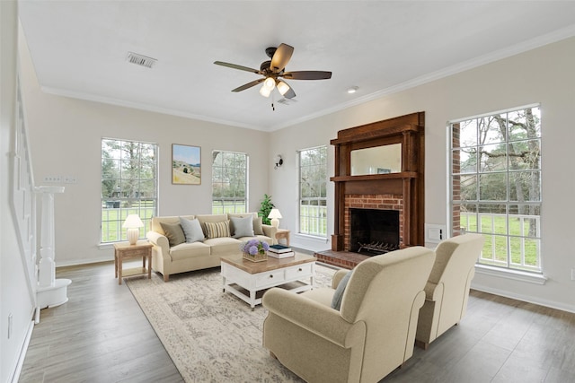 living area with a brick fireplace, ceiling fan, and ornamental molding