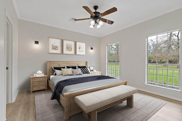 bedroom with visible vents, light wood-style flooring, ornamental molding, a ceiling fan, and baseboards