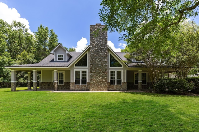 back of property featuring stone siding, a lawn, and a chimney